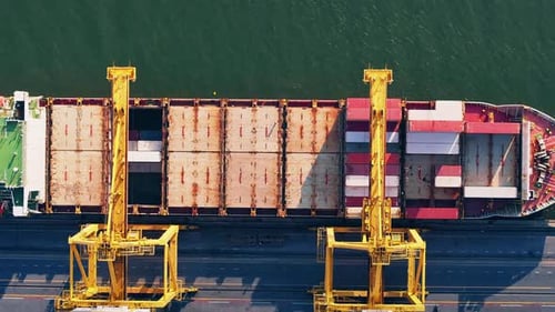 Container ship being loaded at the harbor with cranes near the waterfront
