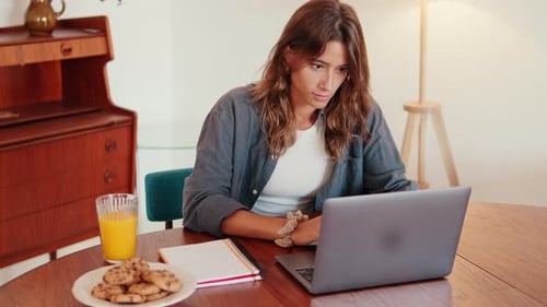Woman Works on Laptop at Table at Home