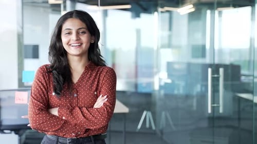 Portrait of young smiling businesswoman standing at workplace in modern business office. Happy