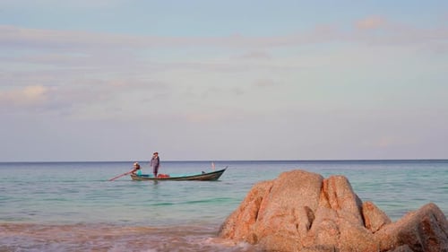 People Rowing a Boat on a Tropical Beach
