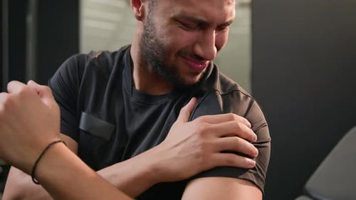 Muscular Man Experiencing Shoulder Pain at Gym