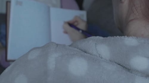 Over-the-Shoulder Focus on Writing in Journal – Blurred Hand and Journal