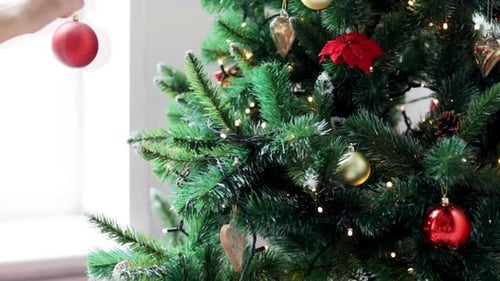 Child Decorating Christmas Tree with Red Bauble
