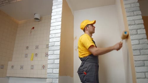 House Painter Paints the Wall in Beige Color