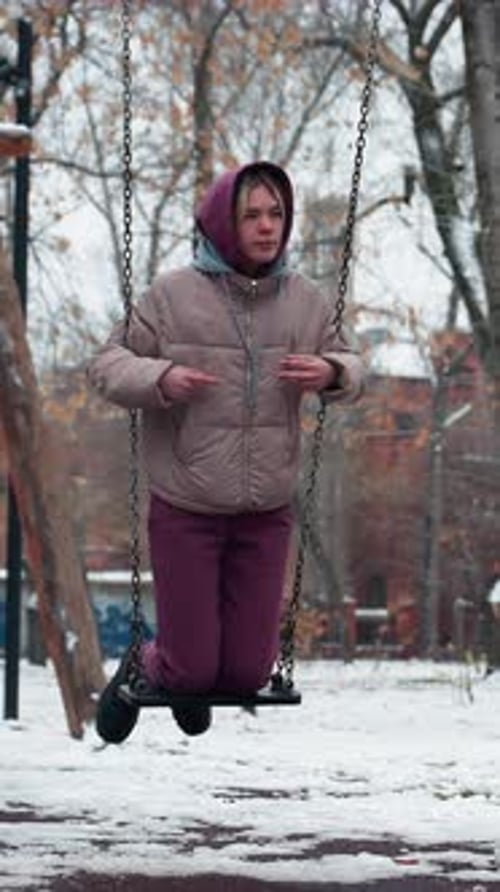 Lady Enjoying Swing on Snowy Winter Day in Park with Snowy Background