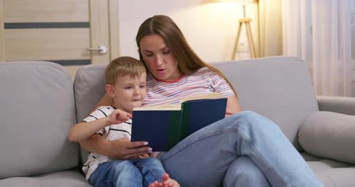 Woman Reading Book with Young Boy on Sofa
