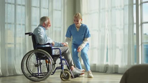 Nurse Assists Senior Man in Wheelchair with Leg