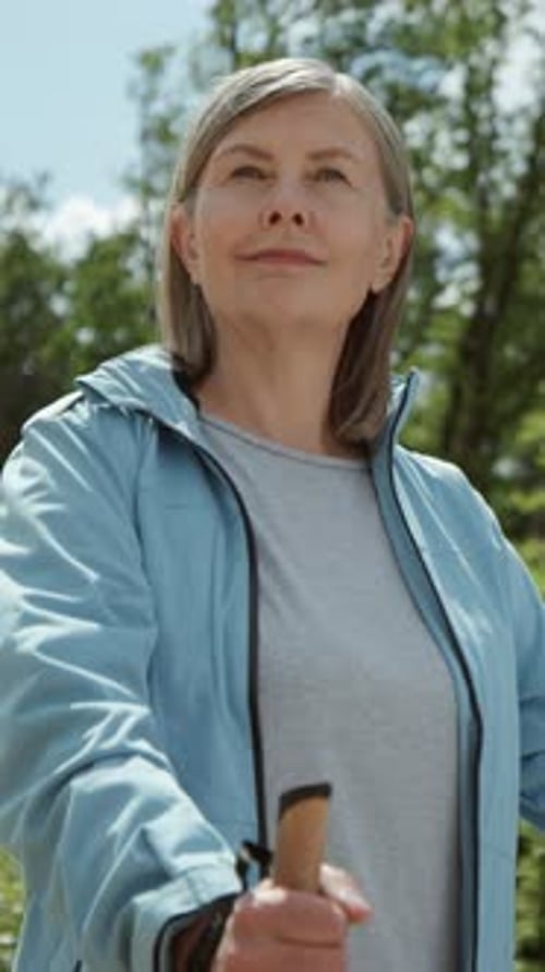 Senior Woman Hikes in Nature With Hiking Poles