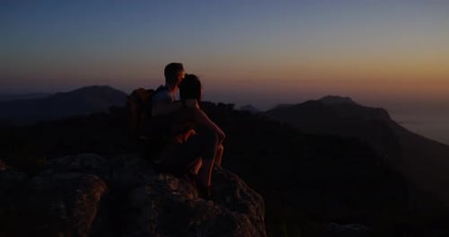 Couple, hiking and summit for adventure, night and mountain top over ocean, standing and silhouette