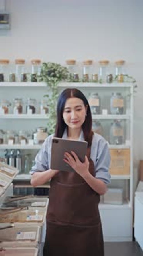 Asian woman shop owner uses a digital tablet