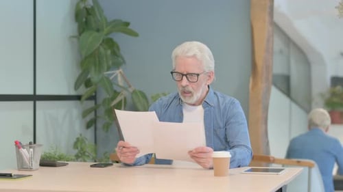 Senior Man Reading Documents at Desk