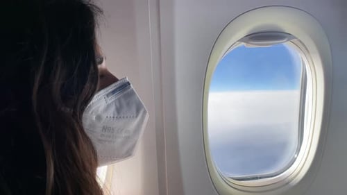 Woman Wearing Mask Looking Out Airplane Window