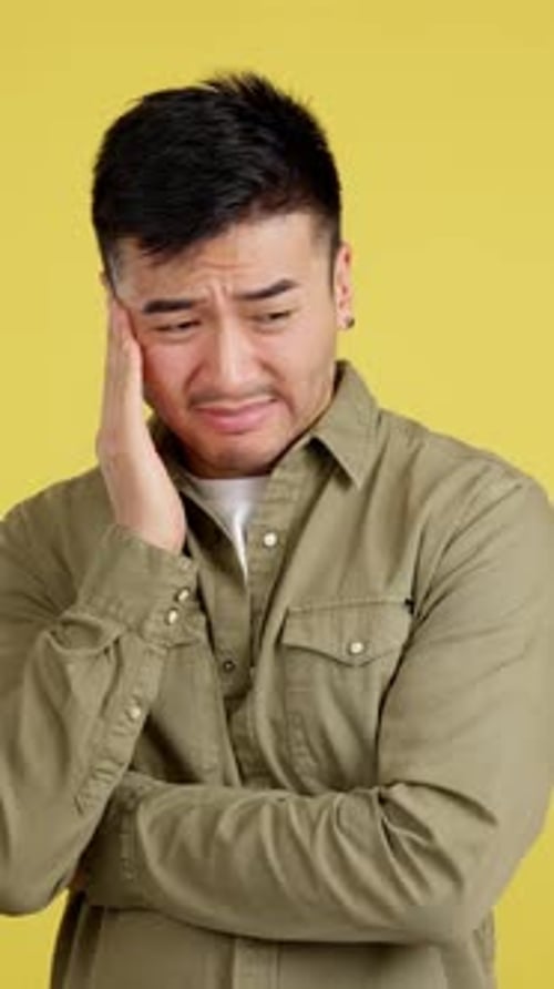 Man Experiencing Toothache Pain Against Yellow Background