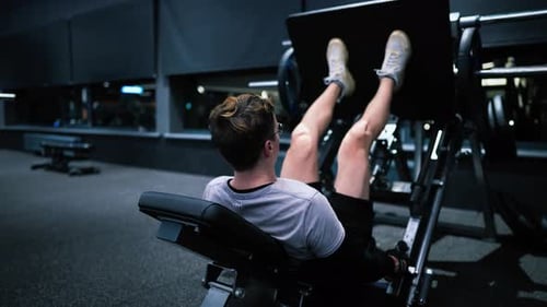 Fitness man exercising in modern gym and doing leg press, weightlifting leg workout slow motion