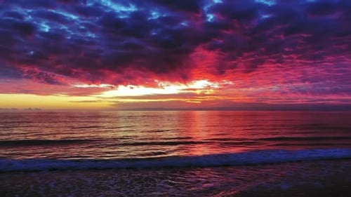 Beautiful ocean sunset with pink, violet and blue clouds and gentle waves.