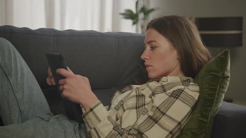 Focused Woman Using Digital Tablet on Living Room in Apartment