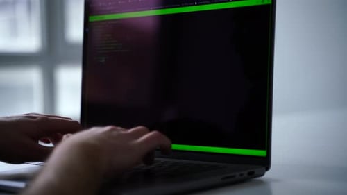 Person typing on computer with green code