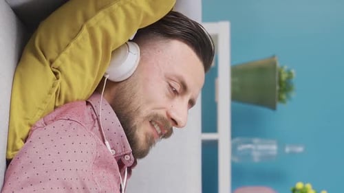 Vertical Video of Cheerful and stylish man listening to music and resting at home.