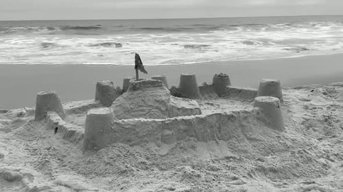 Sand castle on a family beach vacation. Black and white video.