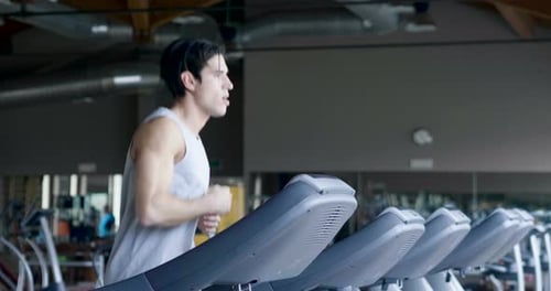 A guy in the gym to stay fit and have defined muscles or lose weight runs on the treadmill with a