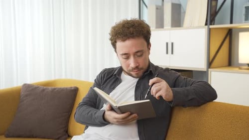 Man Thinking and Writing in Notebook at Home