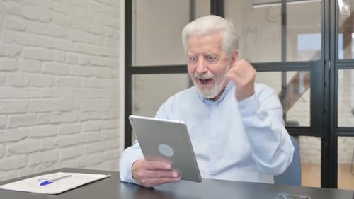 Senior Businessman Celebrating Success on Tablet in Office