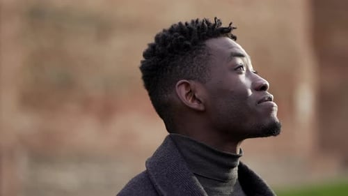 Man Looks Upwards Outdoors on a Cloudy Day