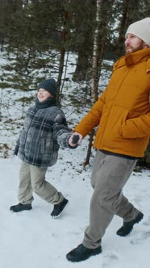 Father and Son Walking Hand In Hand on Snowy Winter Forest Trail