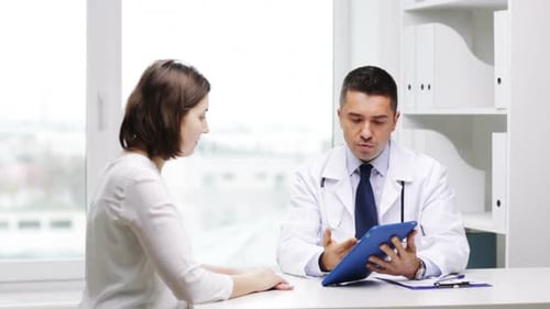 Doctor Consulting with Female Patient Using Tablet in Office