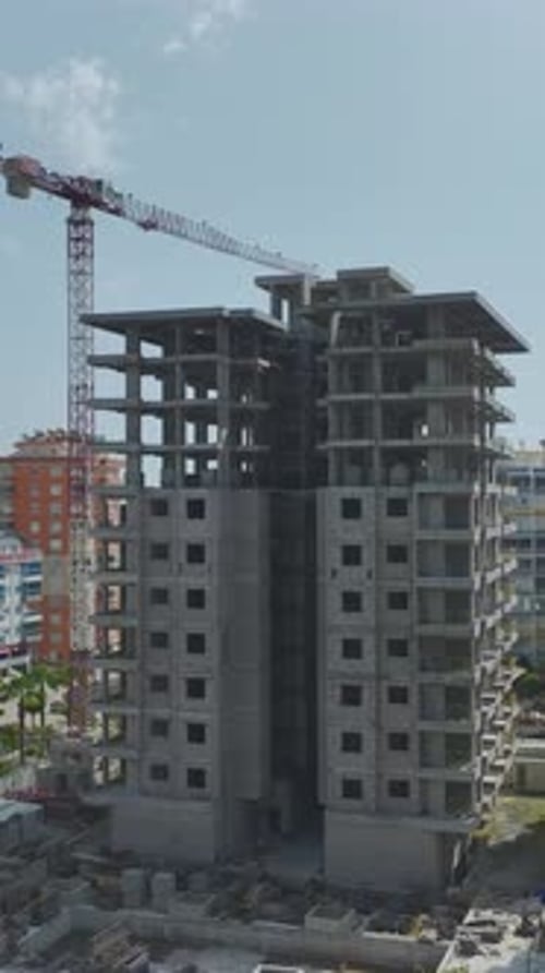 Toma aérea vertical de un edificio de gran altura sin terminar junto a los apartamentos terminados