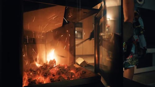 A Woman Keeps a Fire Burning in the Fireplace