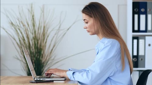 Young Woman Working on a Laptop in a Modern Office Space During the Day