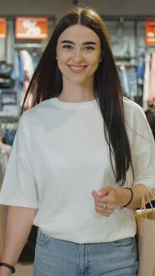 Écran vertical : femmes souriantes marchant avec des sacs de courses dans le centre commercial