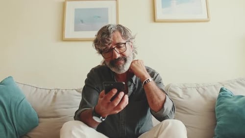 Man Relaxing on Couch Using Smartphone
