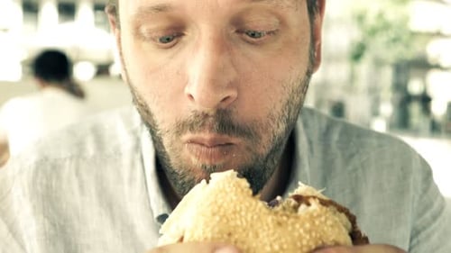 Hungry, Funny Man Eating Burger in City Cafe 30s