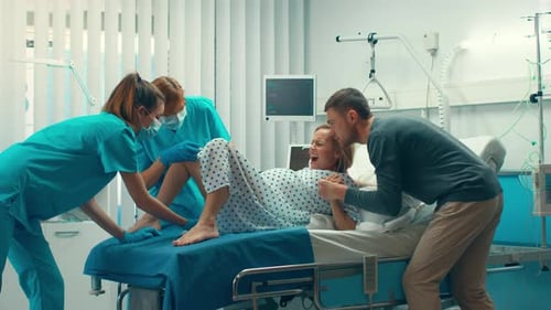 En el hospital, una mujer que da a luz, su esposo la sostiene de la mano en señal de apoyo y los obstetras la ayudan. Modificar