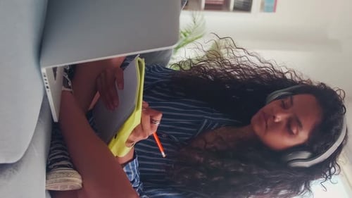 Young Indian Woman Watching Lecture on Laptop and Making Notes in Workbook