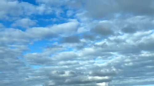 Des cumulus blancs se déplaçant harmonieusement projetant des lumières et des ombres sur un fond de ciel bleu.
Heure