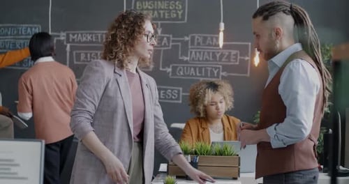 Businesswoman Talking to Male Colleague Discussing Business Strategy Standing in Office Workplace