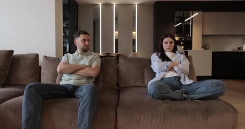 Pareja en disputa sentada en casa, sofá, desacuerdo, brazos cruzados, novio y novia se ignoran