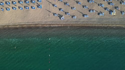 Aerial view of the sea and beach with beach umbrellas and turquoise clear water.