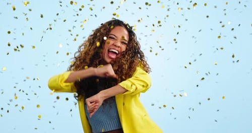 Happy woman, dancing and excited with energy and confetti in studio, fun