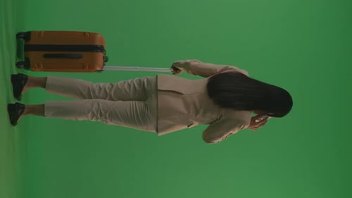 Back View Businesswoman With Luggage Talking On Smartphone While Standing In The Green Screen
