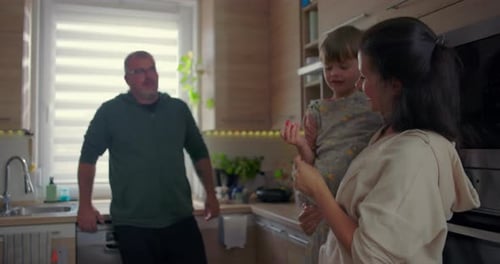 Family in Kitchen, Mother Holds Child, Father Watches