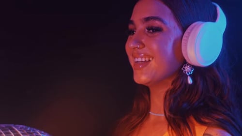 Female DJ in Headphones with Disco Ball Dancing in Club