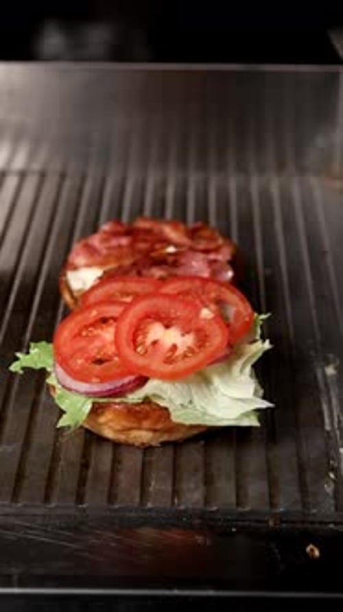 Gloved Hand Assembling a Delicious Burger on Grill