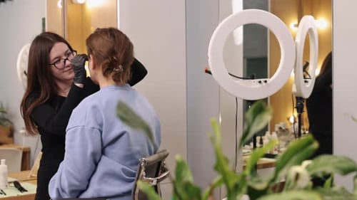 Aesthetician Working On Client Eyebrows in Beauty Salon