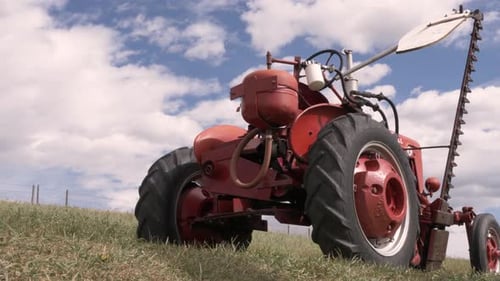 Red tractor stands idle under the sunny sky in a rural farm field