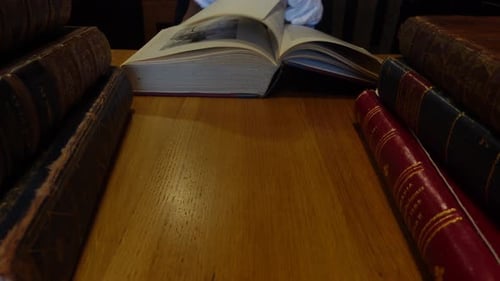 Man leafing through old books at a table
