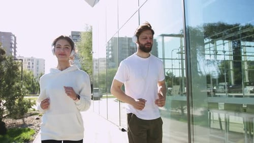 Young Adults Jogging Together Along Urban Sidewalk